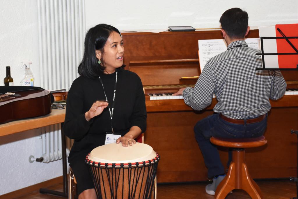 Woman playing a drum alongside a man playing piano at the Institute for Multicultural Ministry
